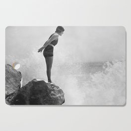 Female swimmer on rock above crashing surf Cutting Board