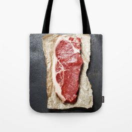 Raw beef steak on a dark slate background Tote Bag