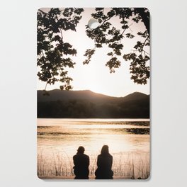 Two girls watching sunset at lake of Banyoles Cutting Board