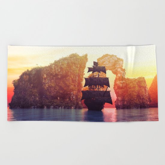 A pirate ship off an island at a sunset Beach Towel