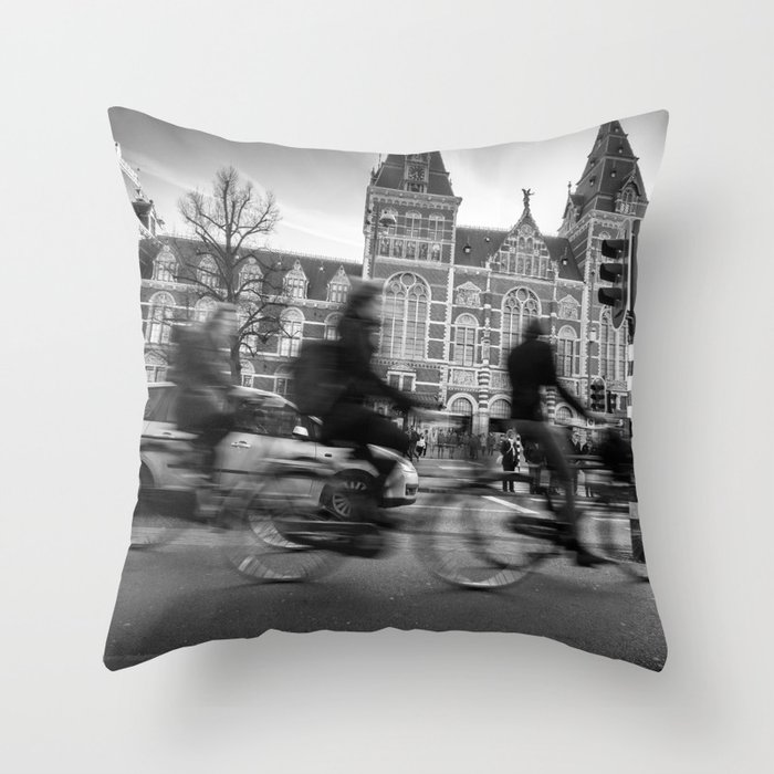 Cyclists ride in Amsterdam street in front of the Rijksmuseum Throw Pillow