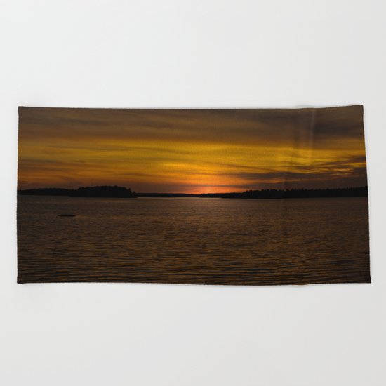 The sun goes down and night falls Beach Towel