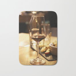 Glass of red wine on a table Bath Mat