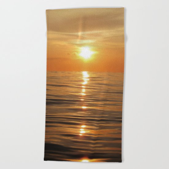 Sun setting over calm waters Beach Towel