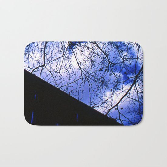Urban maple tree in a winter evening with a city building and a cloudy sky Bath Mat
