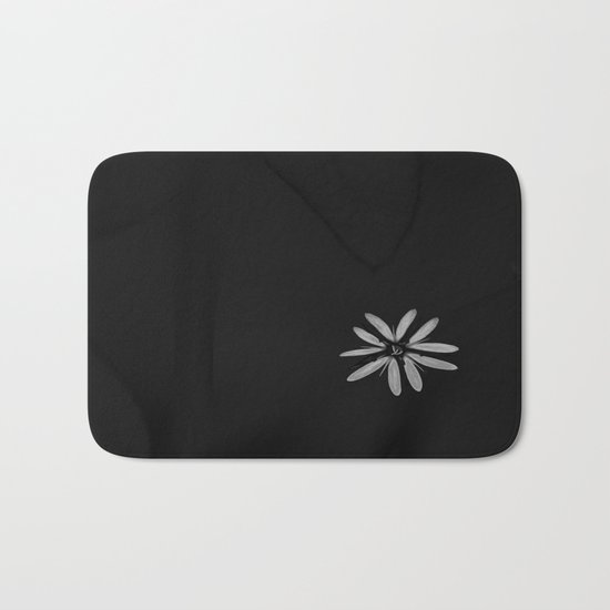 One Tiny White Flower on Black Background Bath Mat
