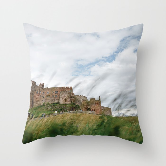 Bamburgh castle through the wild sea grass, Northumberland, England. Throw Pillow