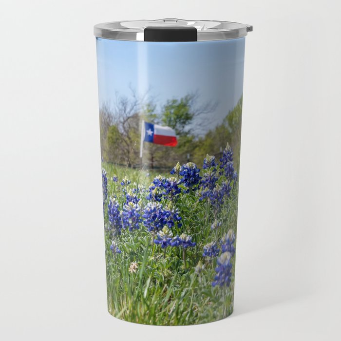 Bluebonnet flowers blooming by road with Texas flag in background Travel Mug