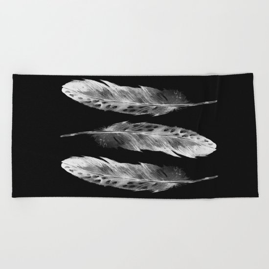 Three feathers on black background Beach Towel