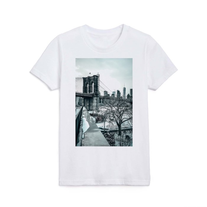 Brooklyn Bridge and Manhattan skyline during winter snowstorm blizzard in New York City Kids T Shirt