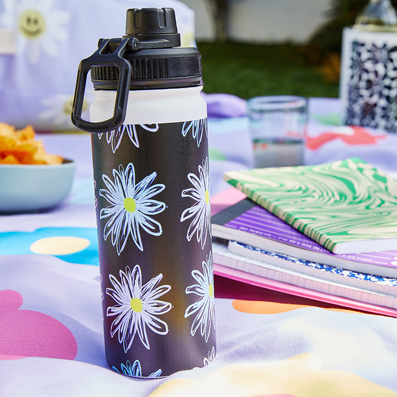 daisy patterned water bottle on an outdoor blanket