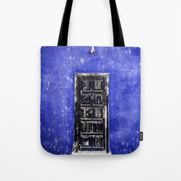 Black worn out door on blue wall Tote Bag