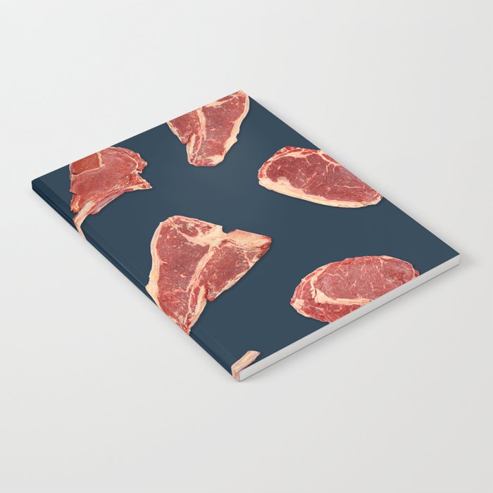 Pattern of fresh beef steaks over blue Notebook