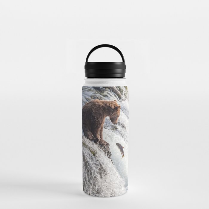 Young grizzly bear sits at waterfall Water Bottle