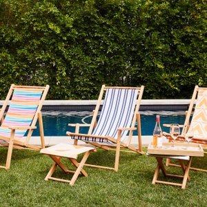 trio of sling chairs on a grassy lawn, next to a pool