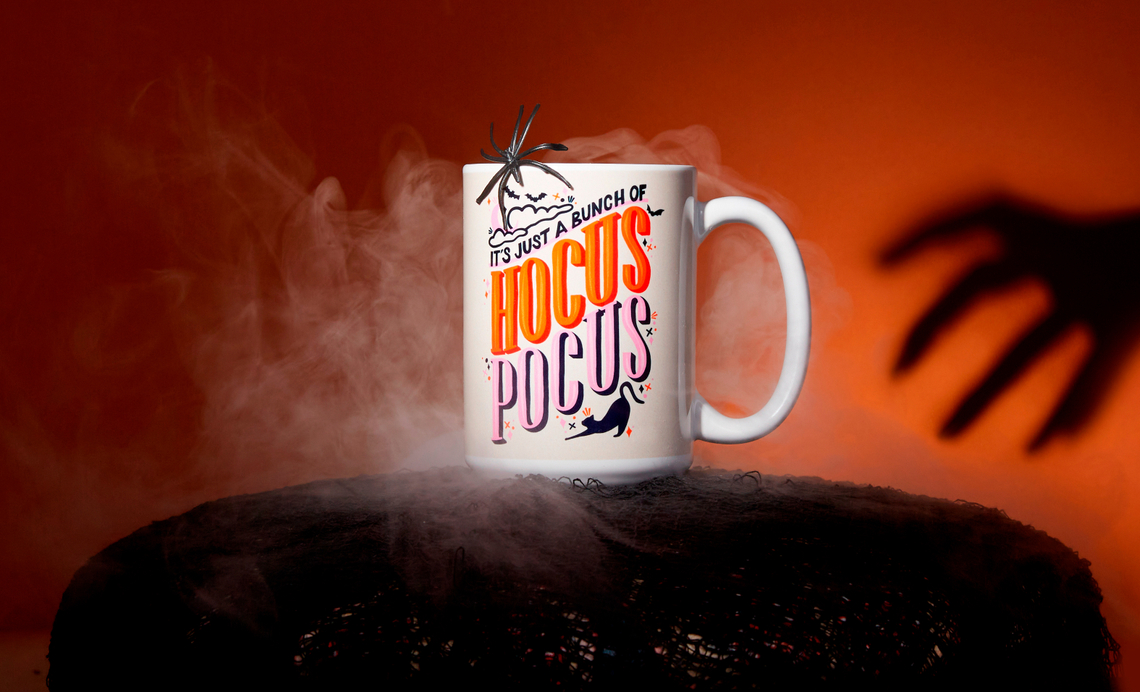 Image of Hocus Pocus mug in a dark orange room with the shadow of a hand creeping up on it. Foggy smoke coming out of mug.