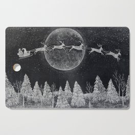Santa flying over a winter wonderland of snow covered trees in his reindeer drawn sleigh by the light of a full moon Cutting Board