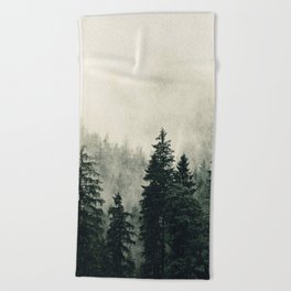 Thick pine forest in the descending mist Beach Towel
