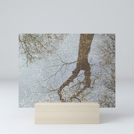 Reflection of trees in a water puddle on the road Mini Art Print