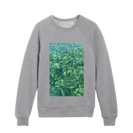 Beach pebbles under a crystal clear green water Kids Crewneck