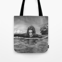 Surfer girl; portrait of young sportswoman in wetsuit on surfing board in ocean at Nusa dua Beach, Bali, Indonesia black and white photograph - photography - photographs by Yuliya Kirayonak  Tote Bag