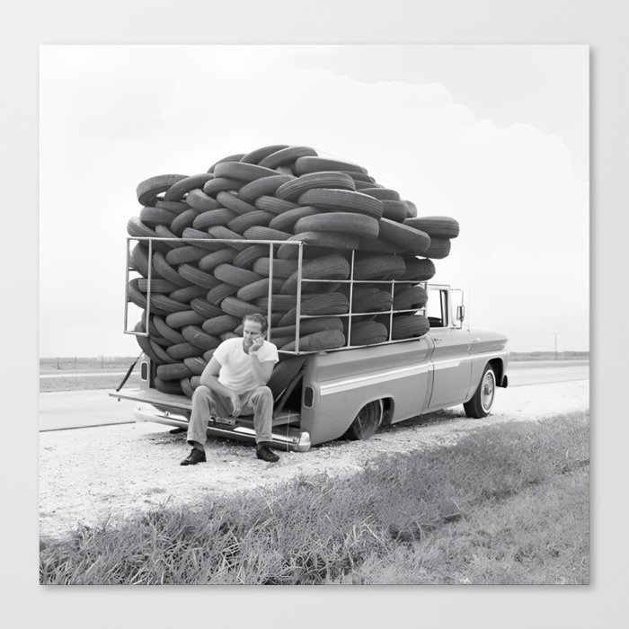 The road to irony is paved with many tires vintage man hauling tires stuck by the side of the road with flat iron black and white funny photograph - photography - photographs Canvas Print