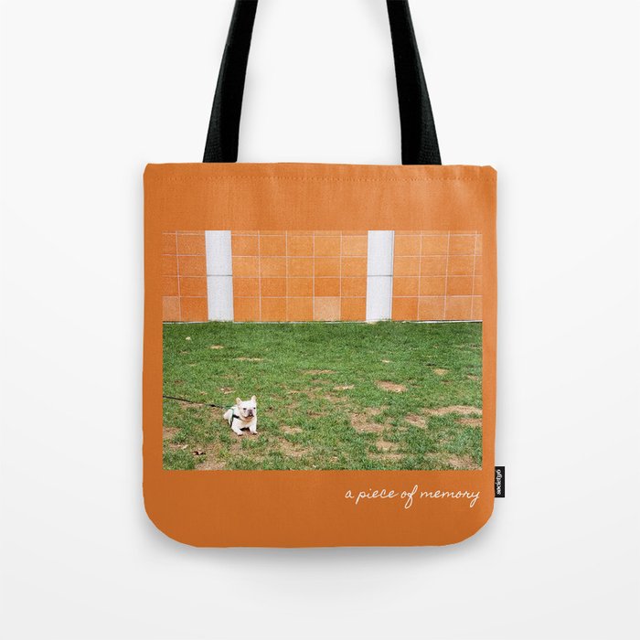 Little French Bulldog | White Small Dog Sitting On The Lawn In Front Of An Orange Wall Tote Bag