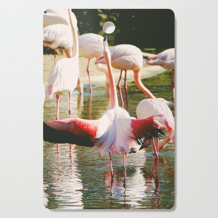 Flamboyance of flamingos | Pink flamingo spreading wings in a lagoon Cutting Board
