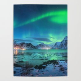 Aurora borealis over the sea coast, snowy mountains and city lights at night. Northern lights in Lofoten islands, Norway. Starry sky with polar lights. Winter landscape with aurora reflected in water Poster
