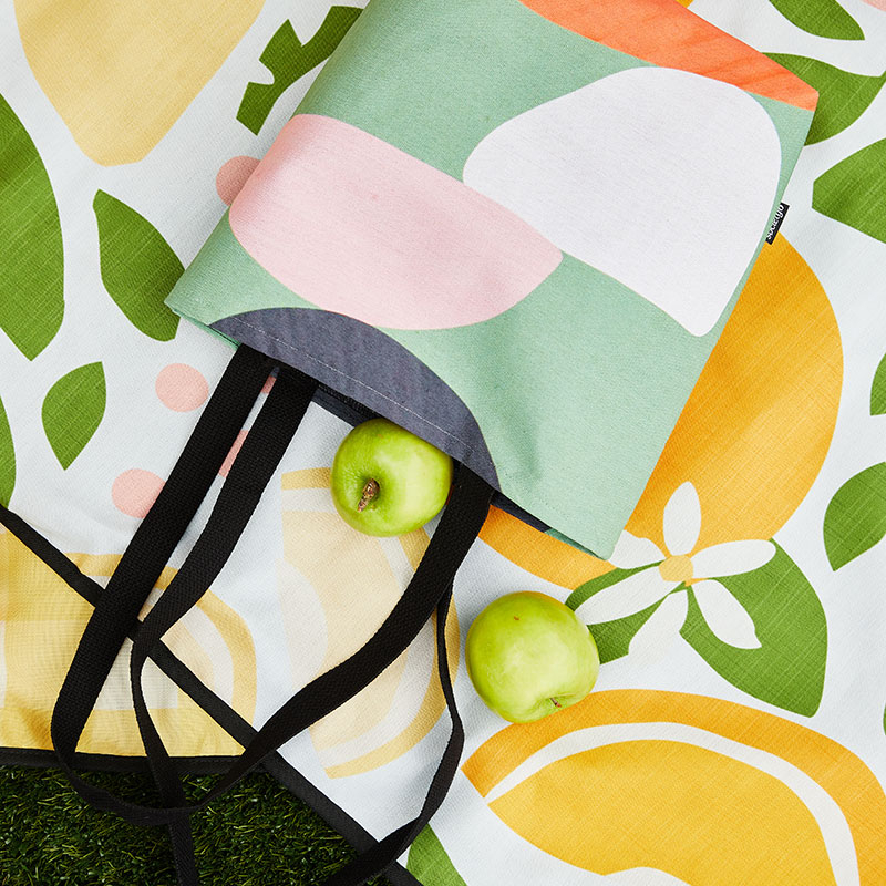 green, pink and white abstract tote bag on an outdoor blanket