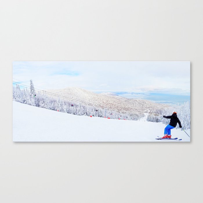 Skier at a ski resort with snowy mountain and lake Canvas Print
