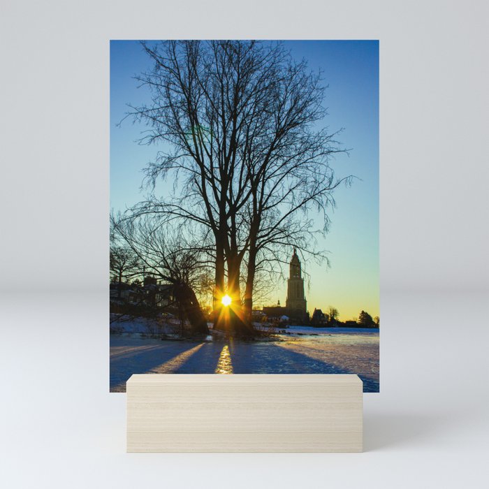 Sunrise on a frozen lake with a little church in the background Mini Art Print