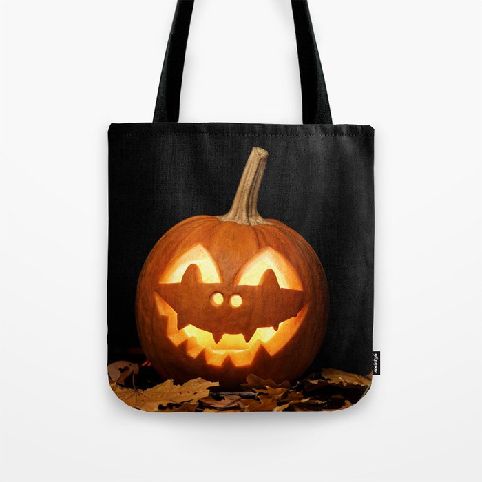 Carved Pumpkin for Halloween and Autumn Leaves on Black Background Tote Bag