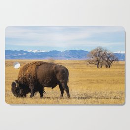 Bison Grazing Beneath the Rocky Mountains in Winter Cutting Board