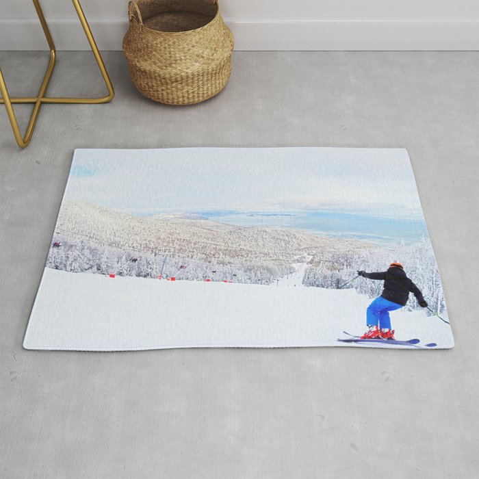 Skier at a ski resort with snowy mountain and lake Rug
