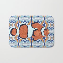 Clownfish swimming on an orange and blue patterned background Bath Mat