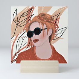 Girl with sunglasses on tan leafy background Mini Art Print