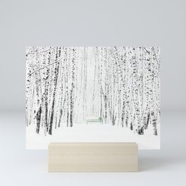 Green bench in white winter forest Mini Art Print