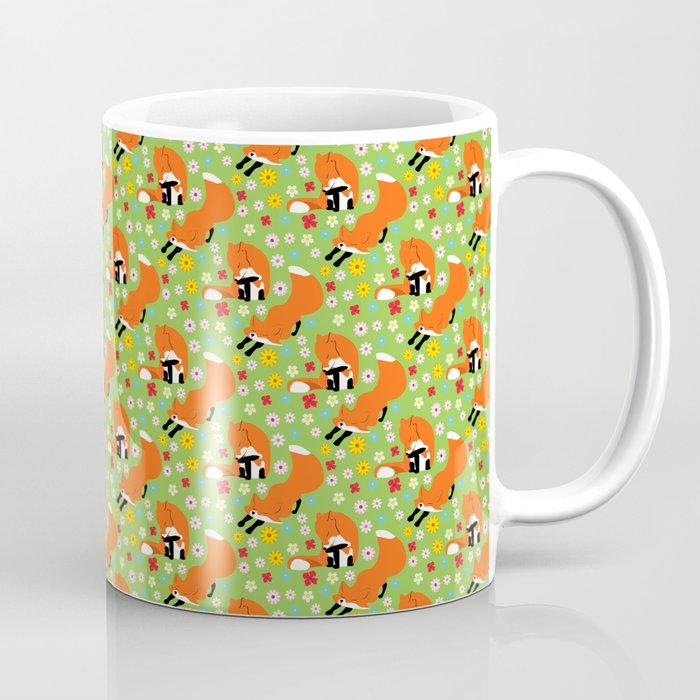 A pair of foxes on field. One stretches, the other licks his paw.  Coffee Mug