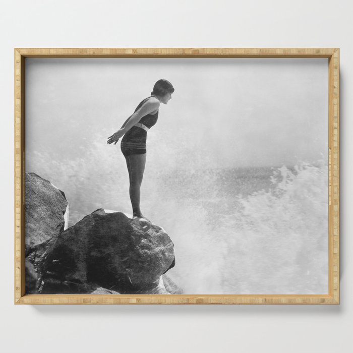 Female swimmer on rock above crashing surf Serving Tray