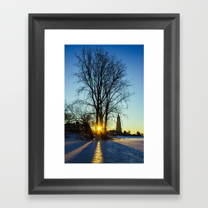 Sunrise on a frozen lake with a little church in the background Framed Art Print