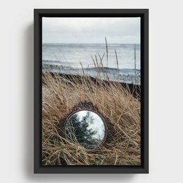 Vintage mirror on seaside reflects forest and sky. Framed Canvas