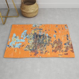 Orange metal background with cracked, peeling paint with stains of blue paint and rust spots. Rug