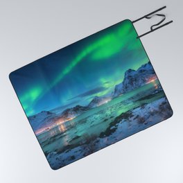 Aurora borealis over the sea coast, snowy mountains and city lights at night. Northern lights in Lofoten islands, Norway. Starry sky with polar lights. Winter landscape with aurora reflected in water Picnic Blanket