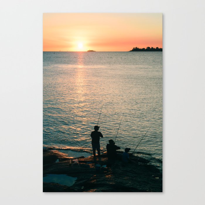 Three fisherman enjoy a beautiful sunset at the shore of 'Colonia del Sacramento, Uruguay'. Canvas Print