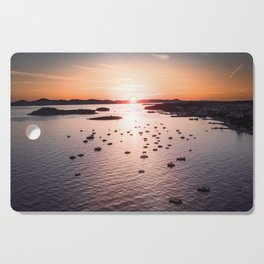 Dramatic sunset on the sea coast with boats in the sea Cutting Board