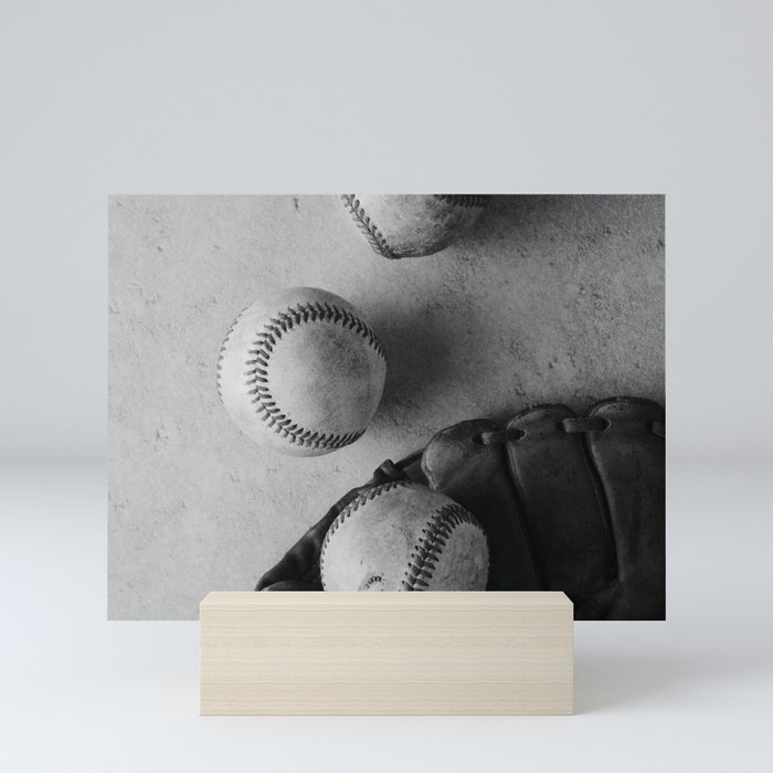 Baseballs used in game with glove in black and white Mini Art Print