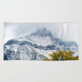 Transitions - Snowy Mountain Peak Overlooking Trees with Fall Color on Autumn Day in Glacier National Park Montana Beach Towel