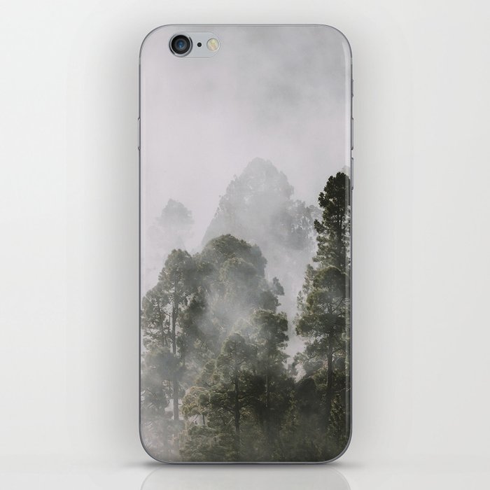 Tall forest trees above the morning mist iPhone Skin