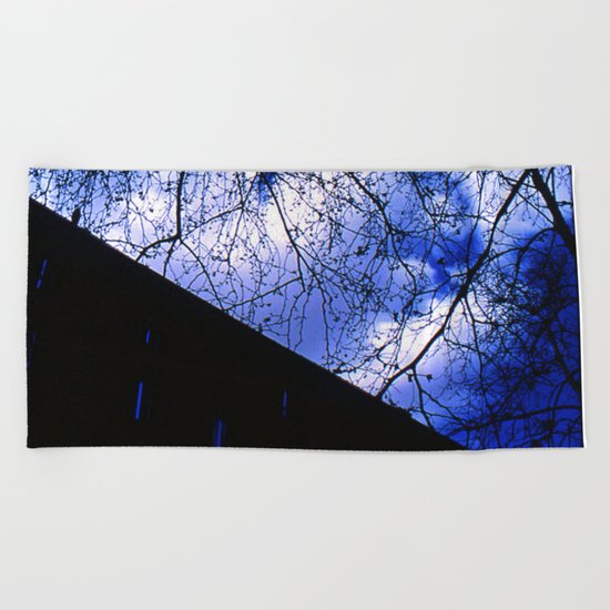 Urban maple tree in a winter evening with a city building and a cloudy sky Beach Towel